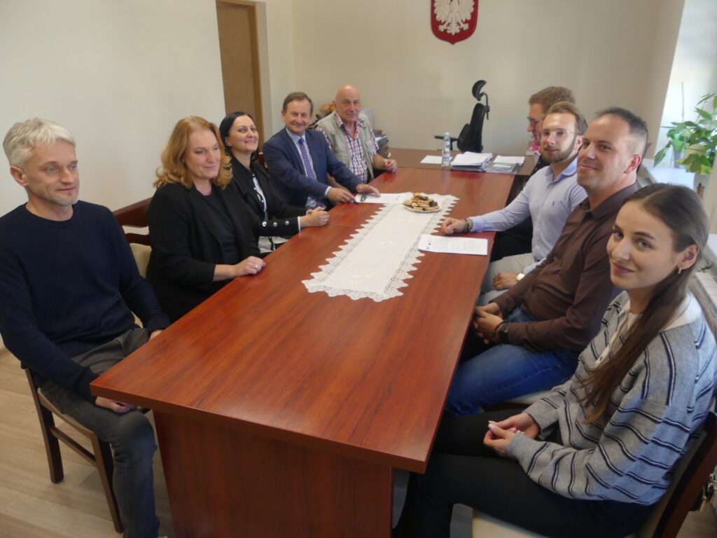 Zdjęcie przedstawia uczestników przekazania terenu i placu budowy do wykonania robót pn.: „Zwiększenie przepustowości istniejącej oczyszczalni ścieków w Krzywczy z unowocześnieniem procesu oczyszczania, w formule zaprojektuj i wybuduj”
